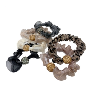 Close-up of six pleated chiffon hair ties with sparkling rhinestone beads in varied patterns
