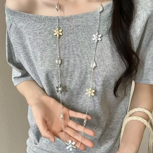 Vue détaillée d'un long collier pull vintage en résine avec breloques fleurs or et argent