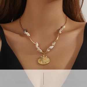 Detail of golden seashell pendant with small pearls and shell beads on a necklace