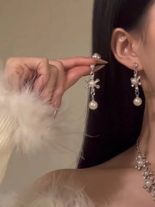 Detail view of flower earrings and pearl necklace jewelry set worn by a model