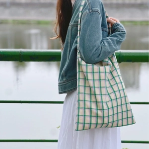Minimalist plaid cotton tote bag with green and purple checkers worn by a model outdoors