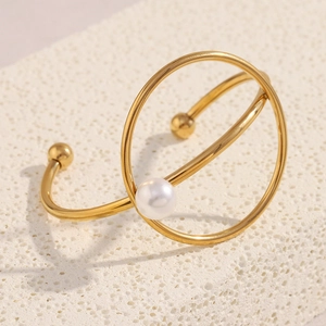 Macro detail of 18K gold plated knotted cuff bracelet featuring a white pearl accent