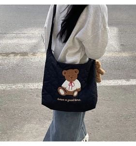 Detail of black quilted tote bag featuring a teddy bear embroidery and have a good time text