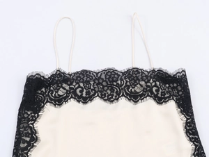 Detail of delicate black lace trim on cream satin camisole with thin shoulder straps