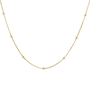 Detaillierte Nahaufnahme einer minimalistischen Gold-Schlangenkette mit runden Perlen