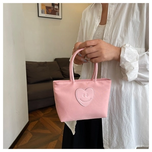 Borsa a mano rosa in nylon con motivo a cuore tenuta da una modella in un interno
