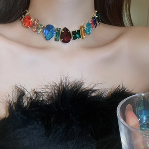 Detail of colorful gemstone choker necklace with gold setting on a model at a party