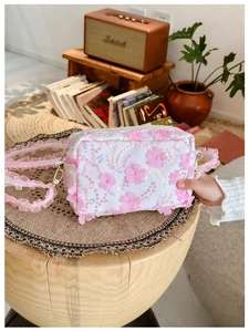 Detailed shot of white floral shoulder bag with 3D pink petals and lace strap