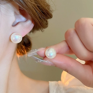 Close-up of elegant iridescent pearl stud earrings with 10mm round beads on ear