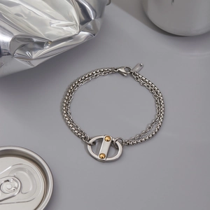 Detail of a dual-layer stainless steel Cuban bracelet with golden rivet decoration