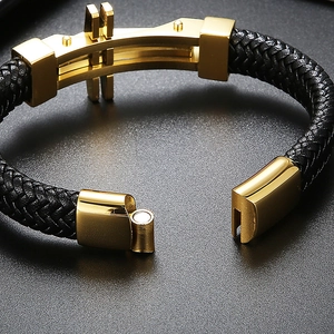 Detail of a men's black braided leather bracelet featuring a gold magnetic clasp