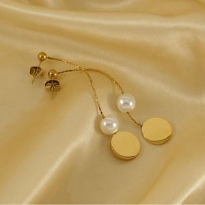 Detailed close-up of 18K gold snake chain earrings with elegant pearls on satin silk