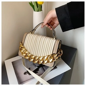 Detail of cream woven handbag with gold chain handle and ruched texture surface