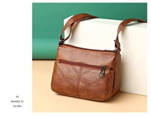 Detail of caramel faux leather bag featuring V-shaped stitching and multi-zipper pockets