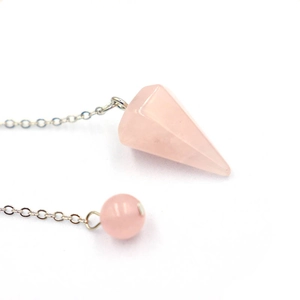 Makroaufnahme von Rosenquarz-Pendel in Hexagonalform mit silberner Kette und Perle