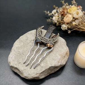 Macro shot of handcrafted moon hair comb with natural dark crystal stones and metal wire details
