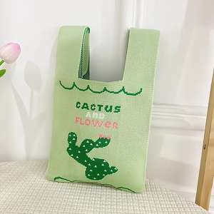 Detail of light green knit tote bag featuring a stitched cactus and textured weave
