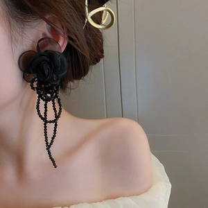 Detail view of French organza flower earrings with black tassels on model for size reference