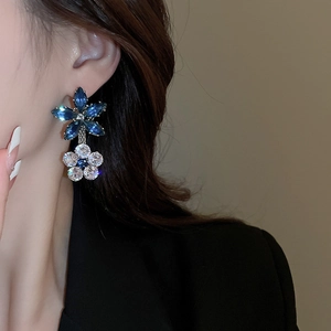 Close-up of blue and clear zircon crystal flower earrings worn by a model