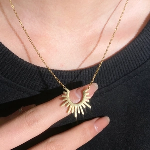 Gros plan du collier avec pendentif tournesol doré et design rayons de soleil sur mannequin