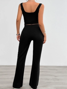 Sleeveless black yoga top and flared trousers set on a minimalist fashion background