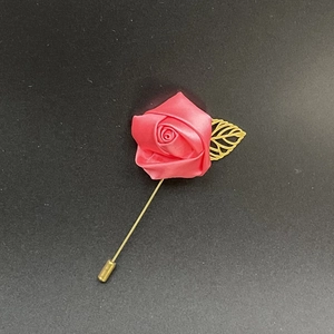 Close-up of pink satin rose brooch with golden hollow leaf and long needle pin