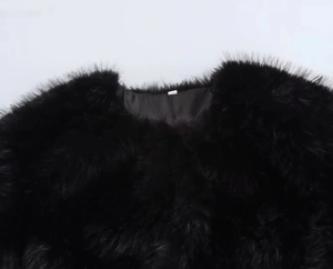 Close-up of high-density black faux fur texture and crew neckline on a short jacket