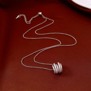 Detailed close-up of triple zircon-set rings on a silver chain over a dark red backdrop