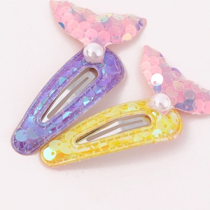 Kids mermaid tail hair clips with shiny sequins and white pearls on pink background