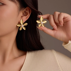 Golden flower petal earrings with a white pearl center shown on a female model