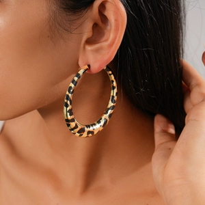 Close-up of model wearing large leopard print hoop earrings with gold accents