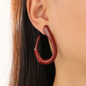 Close-up of deep red geometric drop earring worn by model for a modern fashion look