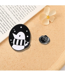 Detailed view of penguin enamel pin with striped scarf on textured surface
