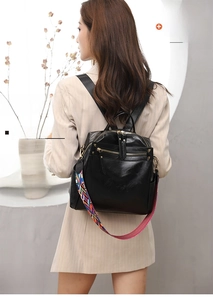 Detail of black soft leather backpack with a colorful ethnic geometric woven shoulder strap