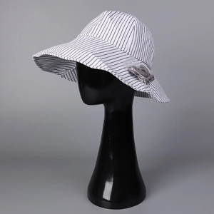 Dettaglio cappello parasole in lino a righe con tesa larga e nodo decorativo sul lato