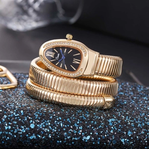 Macro detail of golden snake-shaped bracelet watch with zircon bezel and black dial