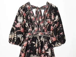 Detail of floral print dress featuring a deep V-neckline and puffed sleeve on black fabric