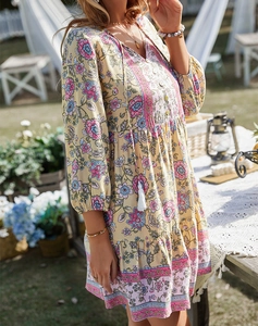 Dettaglio di un abito boho giallo a fiori con nappe sullo scollo a V e gonna a balze
