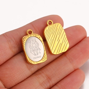 Macro shot of Taurus constellation pendant showing golden textured frame and engraved silver panel