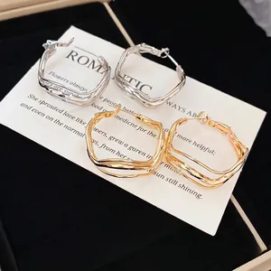 Irregular wavy hoop earrings in gold and silver finish, layered minimalist metal design