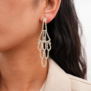 Detail shot of elegant gold fringe chandelier earrings with sparkling rhinestones on model