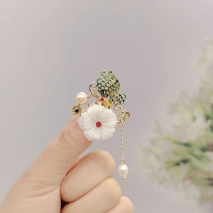 Detail of a gold butterfly flower brooch with red rhinestones and white pearl drop