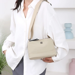 Sac bandoulière minimaliste en nylon beige avec large bandoulière et logo en métal