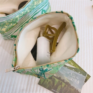 Detailed view of green floral jacquard makeup bag with canvas lining and items inside