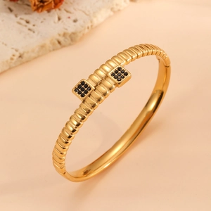 Détail d'un bracelet jonc plaqué or 18k avec d'élégants cristaux carrés noirs sertis