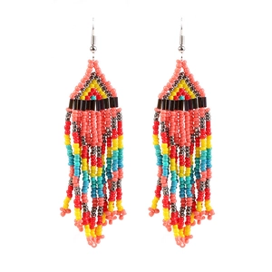 Detailed close-up of handmade bohemian coral pink beaded tassel earrings with fringe