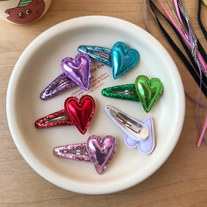 Dettaglio di fermagli per capelli a cuore con paillettes colorate e clip in metallo