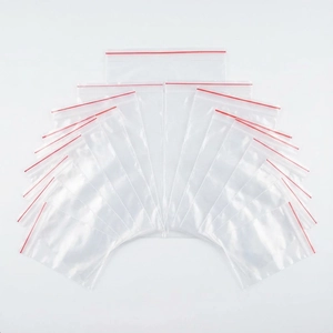 Close-up of transparent PE zip lock bags with red seal strips stacked in a fan pattern