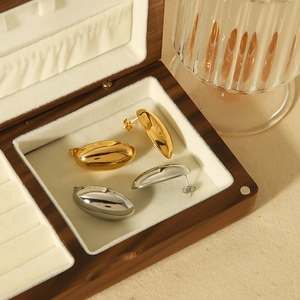 Polished 18k gold and silver oval stainless steel earrings in a wooden jewelry box