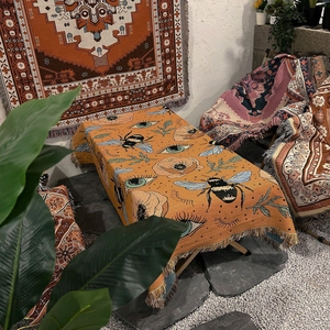 Detail of bohemian yellow throw with woven bee and eye patterns and fringed edges